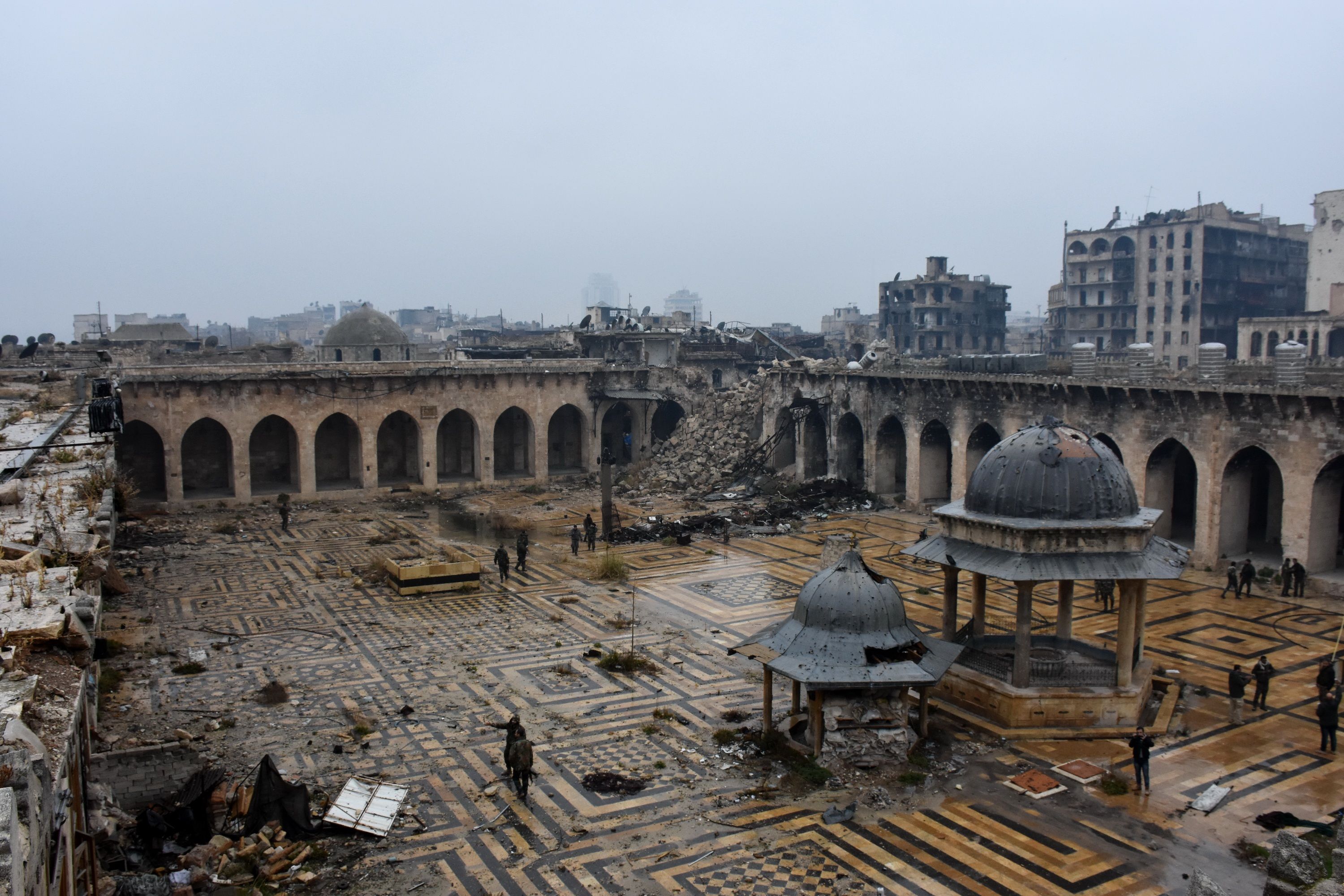 A general view shows Syrian pro-government forces walking in the ancient Umayyad mosque in the old city of Aleppo on December 13, 2016, after they captured the area. After weeks of heavy fighting, regime forces were poised to take full control of Aleppo, dealing the biggest blow to Syria's rebellion in more than five years of civil war.  / AFP / George OURFALIAN