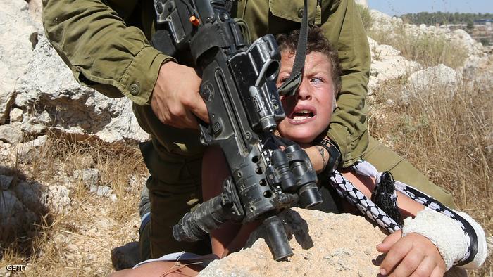 An Israeli soldier controls a Palestinian boy during clashes between Israeli security forces and Palestinian protesters following a march against Palestinian land confiscation to expand the nearby Jewish Hallamish settlement on August 28, 2015 in the West Bank village of Nabi Saleh near Ramallah. AFP PHOTO / ABBAS MOMANI (Photo credit should read ABBAS MOMANI/AFP/Getty Images)