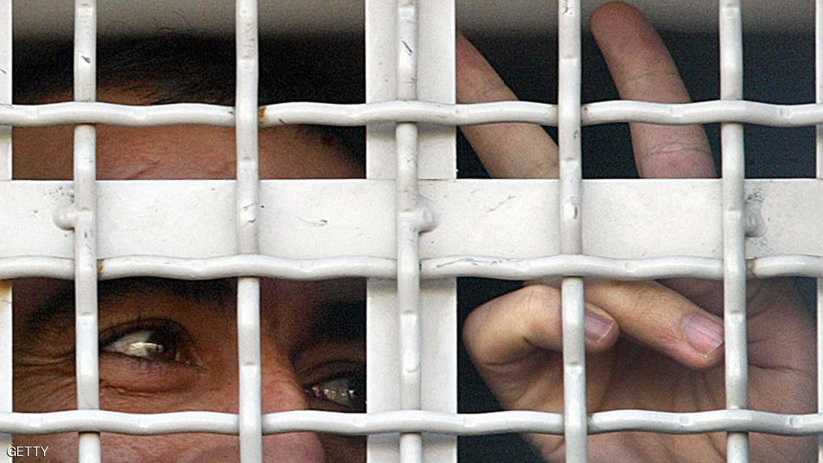 TEL MOND, ISRAEL: Arab prisoners flash the V-sign for victory and peer through the barred window of an Israeli prison truck in Tel Mond, Israel 27 January 2004, as authorities move the prisoners in preparation for their release 29 January, according to a German-brokered prisoners swap deal between Lebanon's Shiite Muslim guerrilla group Hezbollah and Israel. AFP PHOTO/Yoav LEMMER (Photo credit should read YOAV LEMMER/AFP/Getty Images)