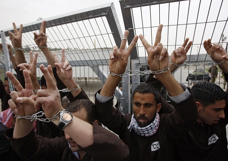 Palestinian protesters gesture with their hands chained during a protest outside Ofer prison near the West Bank city of Ramallah May 1, 2012, in solidarity with hunger striking Palestinian prisoners. The hunger strike against Israel's jail policies has swollen in weeks from a protest by a handful to a national movement with around 1,400 participants. REUTERS/Mohamad Torokman (WEST BANK - Tags: POLITICS CIVIL UNREST)