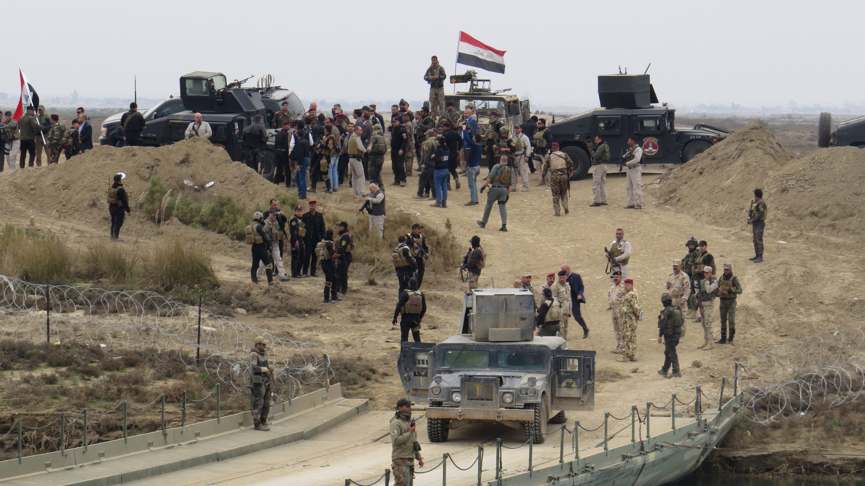 Iraqi security forces gather near a temporary bridge built by the corps of engineers in the Iraqi army south of Ramadi, during a visit by Iraqi Prime Minister Haider al-Abadi on December 29, 2015, after government forces recaptured the city from the Islamic State jihadist group. Abadi visited Ramadi, which lies around 100 kilometres (60 miles) west of Baghdad and is the capital of the province of Anbar, a day after federal forces announced the liberation of the city from the Islamic State group, clinching a landmark victory. AFP PHOTO / STR / AFP / STR (Photo credit should read STR/AFP/Getty Images)