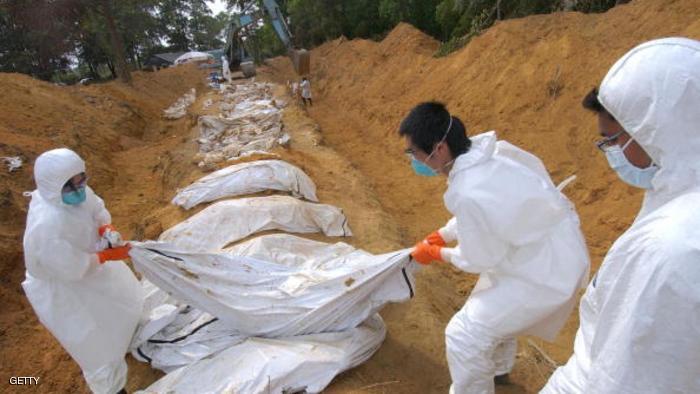 TAKUA PA, THAILAND: Thai volunteers prepare bodies wrapped in cadaver bags for burial at a mass grave for tsunami victims in Takua Pa town, Phang Nga province, in southern Thailand, 07 January 2004. Thailand pressed on with its grim search for tsunami victims 07 January, as officials sought to reassure European nations that no foreigners were buried without identification in mass graves. AFP PHOTO/ROMEO GACAD (Photo credit should read ROMEO GACAD/AFP/Getty Images)