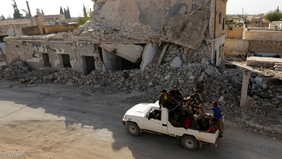 Rebel fighters ride on a pick-up truck past damaged buildings in the northern Syrian rebel-held town of al-Rai, in Aleppo Governorate, Syria, October 5, 2016. REUTERS/Khalil Ashawi