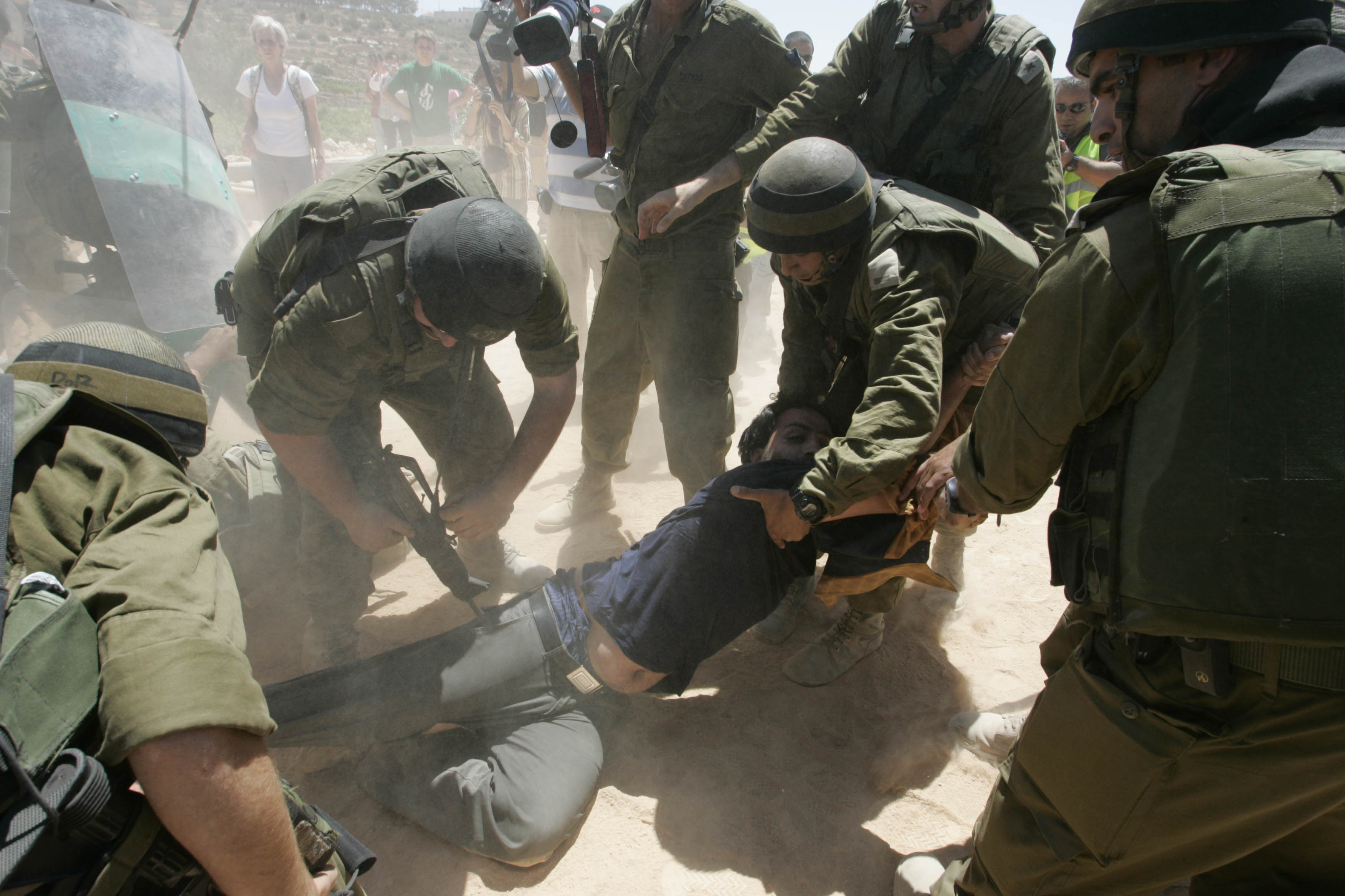 UMM SALAMUNA : Palestinian, Israeli and foreign peace activists are pushed back by israeli soldiers as they protest against the building of the controversial Israeli separation barrier in the West Bank village of Umm Salamuna south of the West Bank city of Bethlehem 13 July 2007. The barrier is a combination of concrete walls and wire fences running more than 650 kilometres (400 miles) north to south that Israel says is necessary to protect it self from Palestinian militants. However, large sections of it encroach on the West Bank, and the Palestinians call it a land grab. The International Court of Justice issued a non-binding ruling in 2004 that parts of the barrier in the West Bank are illegal and should be removed. The barrier is supposed to follow the Green Line that marks Israel's borders before the 1967 Six Day War, when the Jewish state captured the Golan Heights, east Jerusalem, the Gaza Strip and the West Bank, AFP PHOTO MUSA AL-SHAER