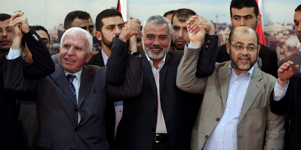 GAZA CITY, GAZA - APRIL 23: Fatah movement Leader Azzam Al-Ahmad (L) and Palestinian Prime Minister Ismail Haniyeh (C) shake hands following the meeting about to end Palestinian divisions between Fatah and Hamas movement in Gaza city, Gaza on April 23, 2014. (Photo by Ali Jadallah/Anadolu Agency/Getty Images)