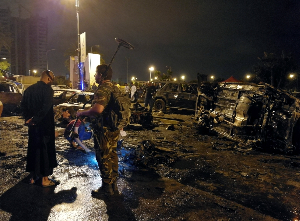 People look at the remnants of a car at the scene of a car bomb in Benghazi, Libya May 25, 2018. REUTERS/Stringer