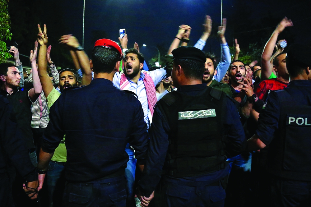 TOPSHOT - Demonstrators confront anti-riot policemen as they protest against against a proposed income tax draft law in front of the Prime Minister's office in Amman, late on June 1, 2018.
Hundreds of Jordanians demonstrated in the capital Amman for a third consecutive day against a proposed income tax draft law aimed at widening the base of tax payers. / AFP PHOTO / STRINGER