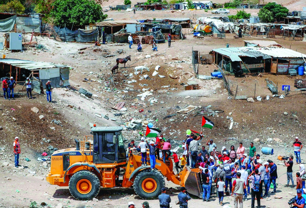 Demonstrators try to prevent a bulldozer from passing through in the Palestinian Bedouin village of Khan al-Ahmar, east of Jerusalem in the occupied West Bank on July 4, 2018.
Khan al-Ahmar, which Israeli authorities say was illegally constructed and the supreme court in May rejected a final appeal against its demolition, is located near several Israeli settlements along a road leading to the Dead Sea. Activists are concerned continued Israeli settlement construction in the area could effectively divide the northern and southern West Bank. / AFP PHOTO / Ahmad GHARABLI