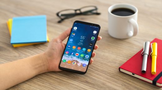 İstanbul, Turkey - February 2, 2019: Hand holding a smart phone on a wooden desk. The smart phone is an Samsung Galaxy S9 plus. Samsung Galaxy is a touchscreen smart phone produced by Samsung Electronics.