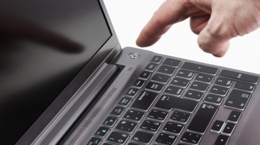 Silver laptop and moving man's hand catching start button, isolated on white background