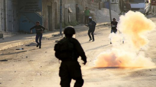 Palestinian protesters throw stones towards an Israeli soldier as smoke rises from a tear gas during clashes in the West Bank city of Hebron April 3, 2013. The death of Maysara Abu Hamdiyeh, a prisoner serving a life sentence over an attempt to bomb an Israeli cafe, from cancer on Tuesday, touched a nerve among Palestinians, who regard their brethren in Israeli jails as heroes in the fight for statehood. Photo by Mamoun Wazwaz