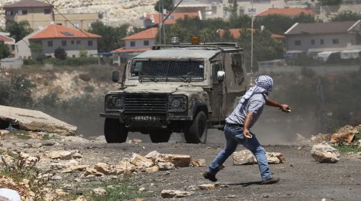 NABLUS, WEST BANK - JUNE 23: A Palestinian protester throws a rock at an Israeli security forces' armed vehicle during a protest against Jewish settlements and the Israeli West Bank barrier at Kafr Qaddum district of Nablus, West Bank in June 23, 2017. (Photo by Nedal Eshtayah/Anadolu Agency/Getty Images)