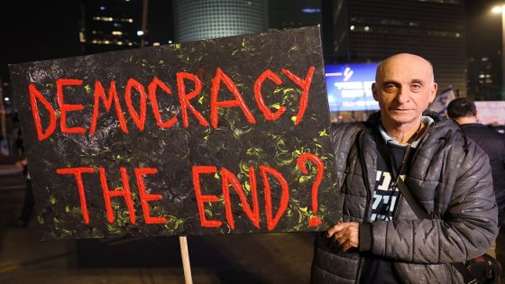 An Israeli holds a placard in Israel's coastal city of Tel Aviv on January 28, 2023, during a protest against controversial government plans to give lawmakers more control of the judicial system. (Photo by JACK GUEZ / AFP)