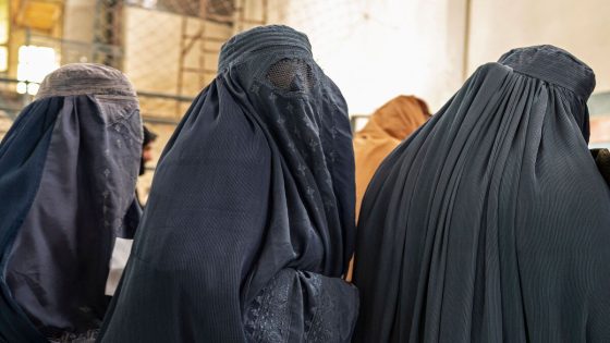 Afghan burqa-clad women stand in a queue as they wait to receive food aid from a non-governmental organisation (NGO) at a gymnasium in Kabul on January 17, 2023. At least three leading international aid agencies have partially resumed life-saving work in Afghanistan, after assurances from the Taliban authorities that Afghan women can continue to work in the health sector. (Photo by Wakil KOHSAR / AFP)