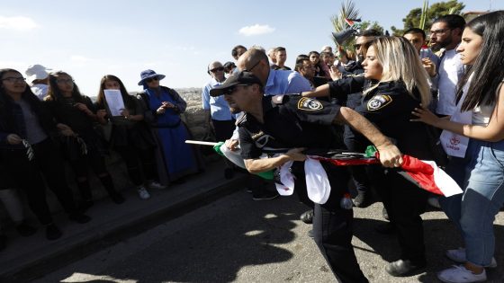 israeli police officer confiscates a palestinian flag from christian palestinians Roman Catholic clergy take part in the traditional Palm Sunday procession from Mt. Olives to Jerusalem's Old City on March 25, 2018. The ceremony is a landmark in the Christian calendar, marking the triumphant return of Christ to Jerusalem the week before his death, when a cheering crowd greeted him waving palm leaves. Palm Sunday marks the start of the most solemn week in the Christian calendar.PHOTO/GALI TIBBON