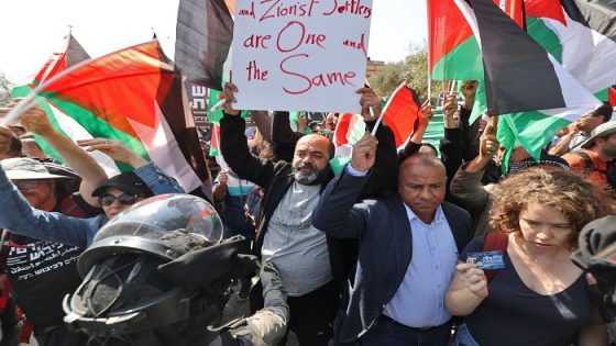 Palestinian and Israeli peace activists protest at the entrance of Huwara in the occupied West Bank, on March 3, 2023, following deadly violence by Israeli settlers. - Late on February 26, the Palestinian town of Huwara came under attack by Israeli settlers, hours after two settlers were shot dead as they drove through the northern West Bank town. (Photo by JAAFAR ASHTIYEH / AFP)