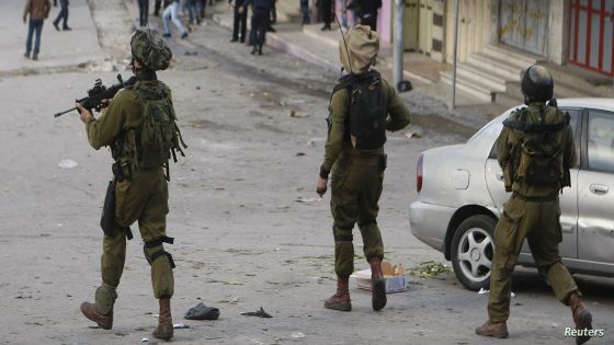 Israeli soldiers walk with their weapons behind a group of Palestinians during clashes in the West Bank city of Hebron December 6, 2012. A statement from the IDF (Israeli Defence Force) said that following an incident between Israeli soldiers and Palestinian police on Thursday, some 250 Palestinian rioters gathered at the scene and hurled rocks towards the soldiers who responded by firing tear gas to disperse them. REUTERS/Mussa Qawasma (WEST BANK - Tags: POLITICS CIVIL UNREST)