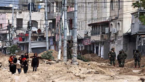 Palestinians leave their homes for safety as Israeli soldiers stand during a raid in the Nur Shams refugee camp near Tulkarem in the occupied West Bank on February 10, 2025. (Photo by Zain JAAFAR / AFP) (Photo by ZAIN JAAFAR/AFP via Getty Images)