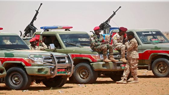 Members of Sudanese paramilitary Rapid Support Forces (RSF) celebrate as they lead dozens of African nationals, caught as they tried to cross into Libya illegally, in front of the media a desert area called Gouz Abudloaa, about 100 kilometres north of Khartoum, on September 25, 2019. - Sudanese paramilitaries said they have captured 138 Africans, including dozens of Sudanese, trying to enter neighbouring Libya illegally. (Photo by ASHRAF SHAZLY / AFP) (Photo credit should read ASHRAF SHAZLY/AFP via Getty Images)