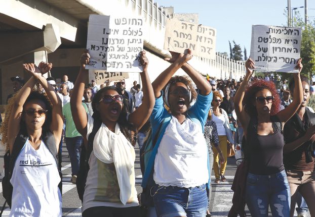 Israelis from the Ethiopian community in Jerusalem hold banners as they take part in a demonstration near a major junction in the city on April 30, 2015 against "racism from the police". AFP PHOTO / GALI TIBBON