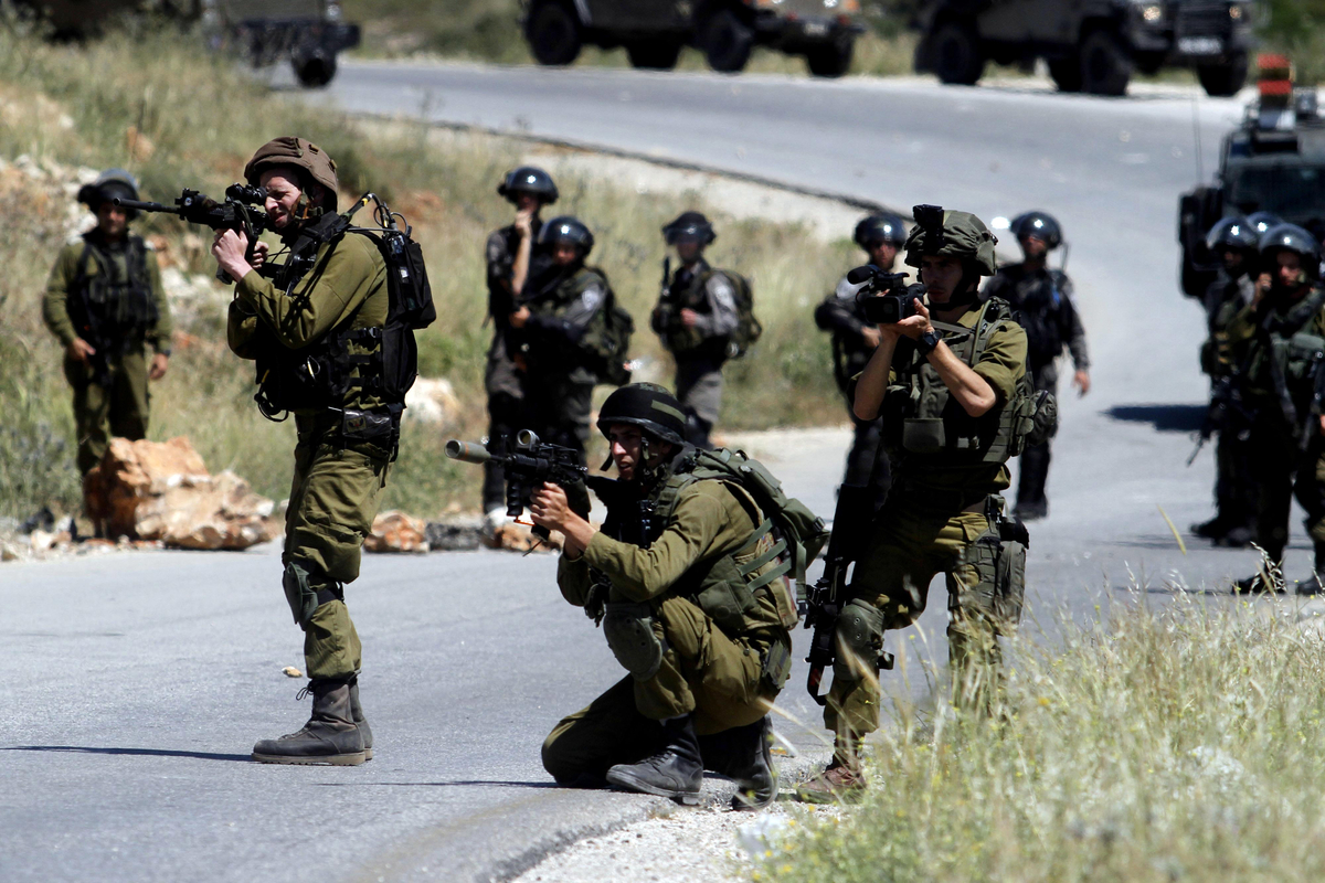 Israeli security forces aim their guns towards Palestinian protesters during clashes following a weekly demonstration against the expansion of settlements in the Israeli-occupied West Bank, on May 2, 2014 in the village of Nabi Saleh, near Ramallah. Photo by Issam Rimawi