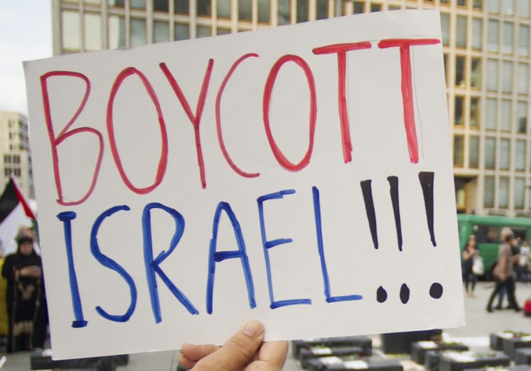 A woman holds a sign which reads "Boycott Israel" in front of symbolic coffins while attending a demonstration supporting Palestine, in Berlin August 1, 2014. Israel launched its Gaza offensive on July 8 in response to a surge of rocket attacks by Gaza's dominant Hamas Islamists. Hamas said that Palestinians would continue confronting Israel until its blockade on Gaza was lifted. REUTERS/Steffi Loos (GERMANY - Tags: POLITICS CIVIL UNREST) - RTR40YJG