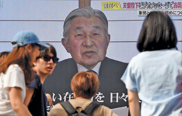 People look at a big video screen on the street as a speech by Japanese Emperor Akihito to the nation is televised in Tokyo on August 8, 2016. Emperor Akihito said on August 8 he is concerned his weakening health may make it hard to fulfil his duties, in a speech seen as signalling a possible future abdication. / AFP / TORU YAMANAKA