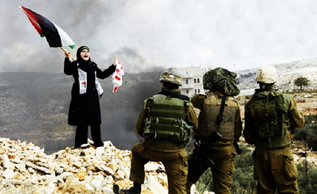 A Palestinian stands in front of Israeli soldiers during a protest in the West Bank village of Bilin near Ramallah against Israel's offensive in Gaza January 8, 2009. Several rockets fired from Lebanon struck northern Israel on Thursday, slightly wounding two people, police and medics said, in attacks seen as linked to Israel's war on Hamas Islamists in the Gaza Strip. REUTERS/Eric Gaillard (WEST BANK)