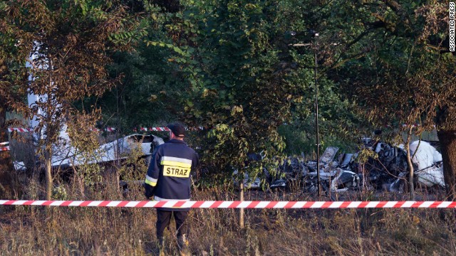 A firefighter officer examines the crash site of a plane near the village of Topolow in Poland, Saturday, July 5, 2014. The small Piper Navajo aircraft carrying parachutists crashed and burst into flames shortly after takeoff, killing several people and injuring at least one. (AP Photo)