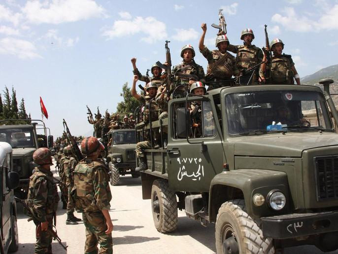 In this photo taken during a government-organized visit for media, Syrian army soldiers shout slogans in support of Assad as they enter a village near the town of Jisr al-Shughour on June 10. Ongoing military operations to crush anti-government protest are draining money from the national budget.