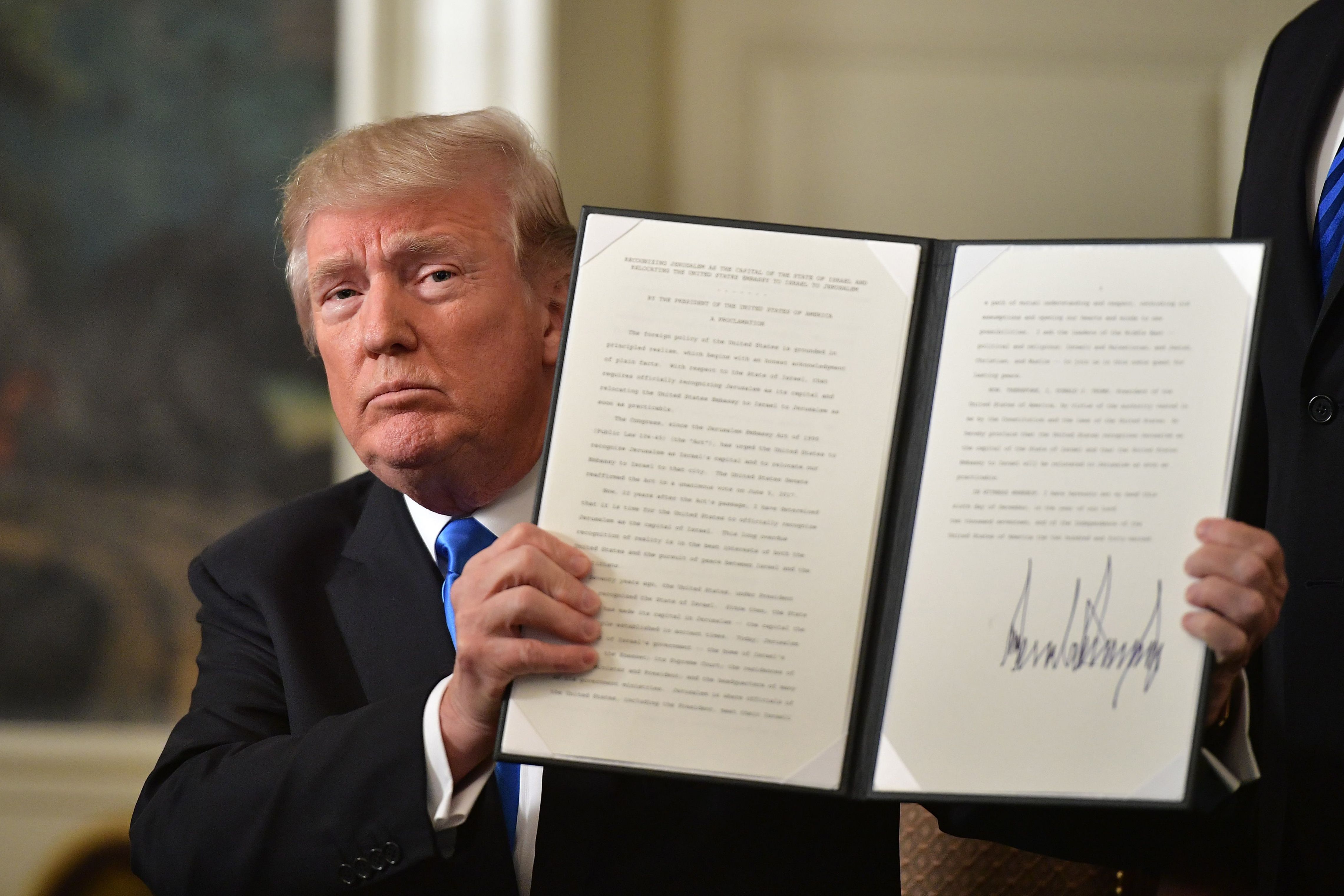 US President Donald Trump holds up a signed memorandum after he delivered a statement on Jerusalem from the Diplomatic Reception Room of the White House in Washington, DC on December 6, 2017. President Donald Trump on Wednesday recognized the disputed city of Jerusalem as Israel's capital -- a historic decision that overturns decades of US policy and risks triggering a fresh spasm of violence in the Middle East."I have determined that it is time to officially recognize Jerusalem as the capital of Israel," Trump said from the White House."It's the right thing to do." / AFP PHOTO / MANDEL NGAN