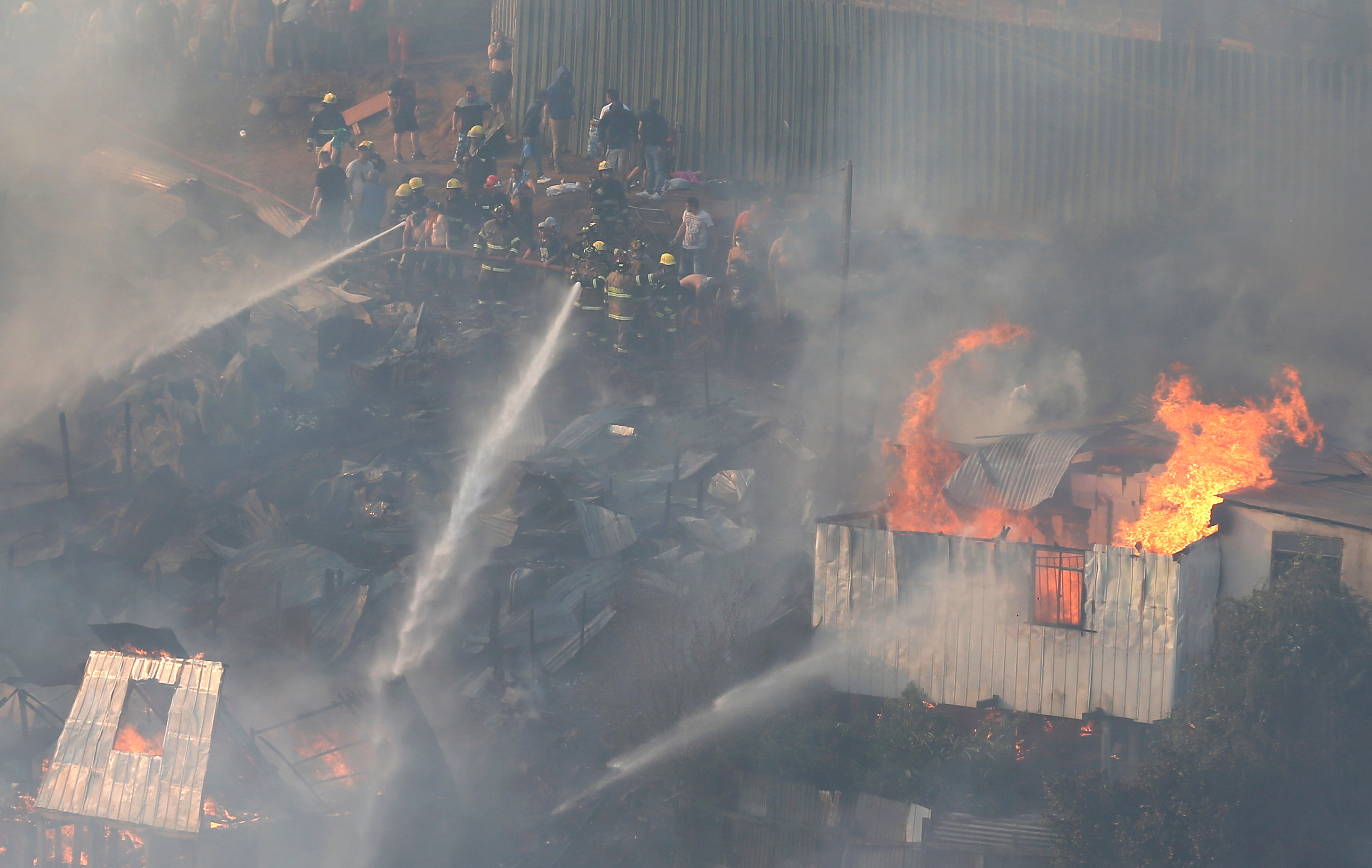 Firefighters work to put out a fire in a house on a hill, where more than 100 homes were burned due to a forest fire but there have been no reports of death, local authorities said in Valparaiso, Chile January 2, 2017. REUTERS/Rodrigo Garrido