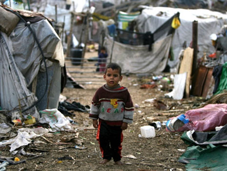An impoverished Palestinian boy walks amidst shacks and rubbish at a poverty-stricken southern Gaza City neighborhood on November 12, 2008. The United Nation says more than half of residents in the Gaza Strip are living under the poverty line. Living conditions in Gaza have deteriorated because of the two-year long Israeli blockade imposed by Israel against the territorys Hamas rulers. AFP PHOTO/MAHMUD HAMS