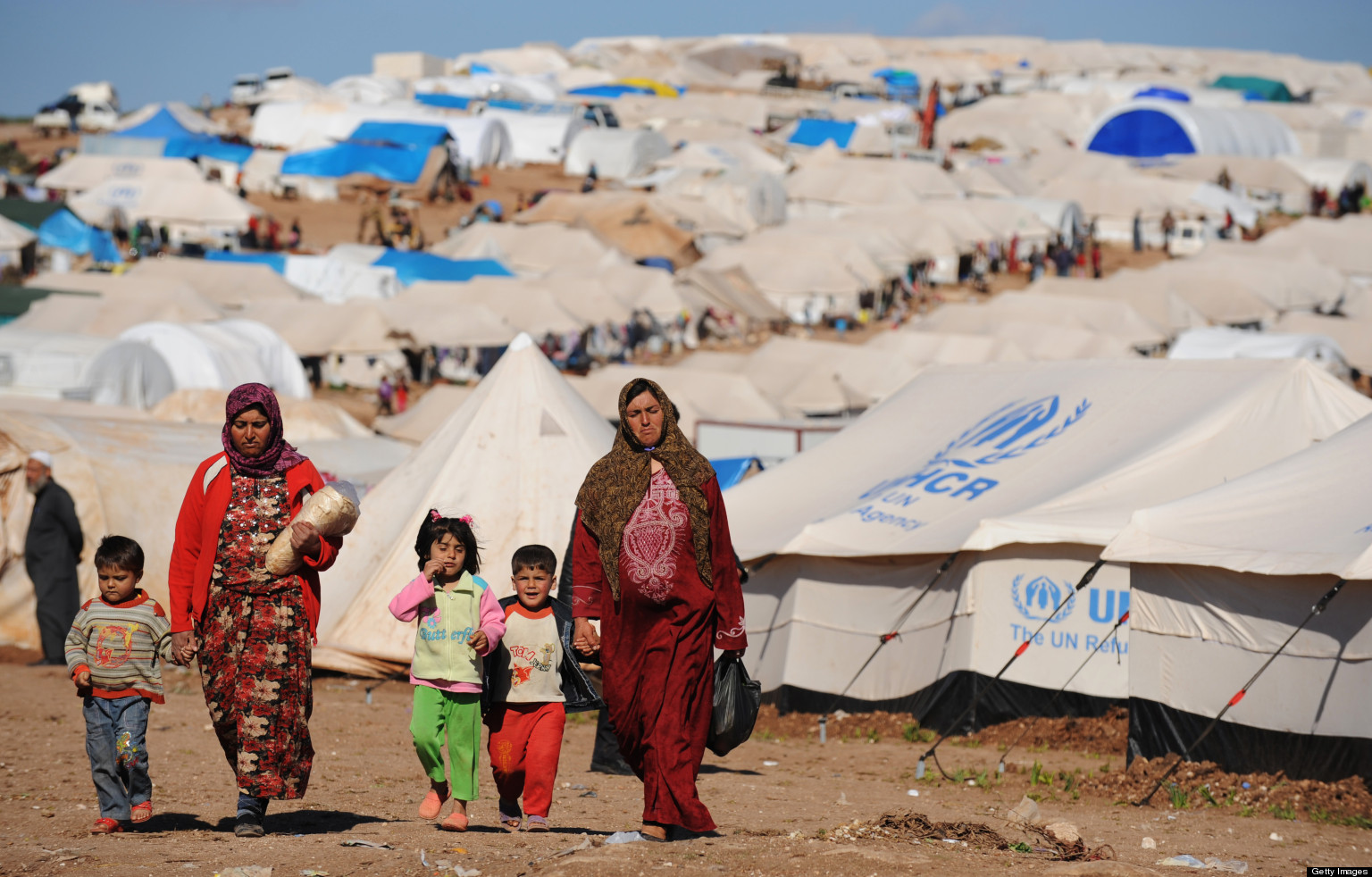 Syrian internally displaced people walk in the Atme camp, along the Turkish border in the northwestern Syrian province of Idlib, on March 19, 2013. The conflict in Syria between rebel forces and pro-government troops has killed at least 70,000 people, and forced more than one million Syrians to seek refuge abroad. AFP PHOTO/BULENT KILIC (Photo credit should read BULENT KILIC/AFP/Getty Images)